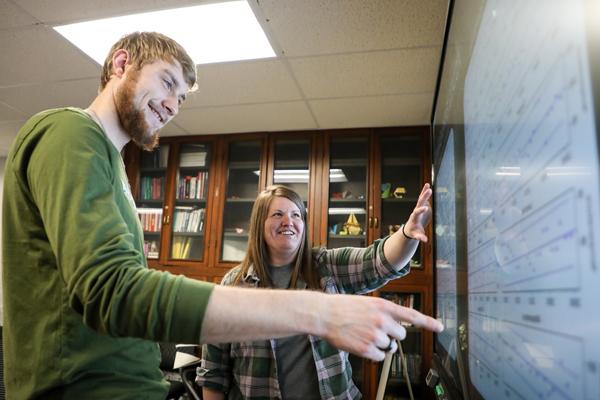 Man and woman pointing at graphs on a smartboard